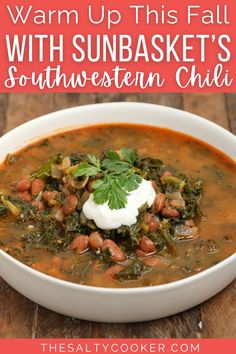 a bowl of soup with spinach, beans and sour cream in it on a wooden table