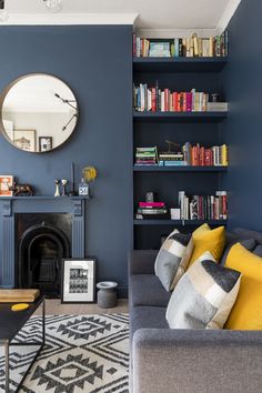 a living room filled with furniture and a clock mounted to the wall above a fireplace