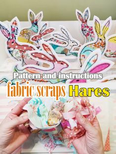 two hands are holding fabric scraps in front of some paper rabbits