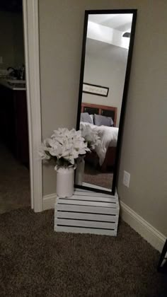 a mirror sitting on top of a white table next to a vase filled with flowers