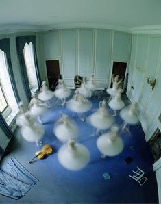 a group of ballerinas are dancing in a room with blue carpet and white walls