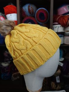 a yellow knitted hat sitting on top of a mannequin's head