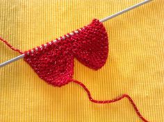 an orange piece of cloth with red yarn on it next to a needle and thread