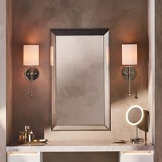 a bathroom vanity with two lights and a mirror on the wall next to it,