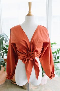 a mannequin wearing an orange top with a bow