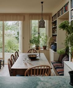 a dining room table with chairs and a bowl on it in front of a window