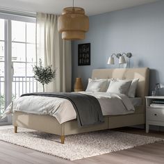 a bedroom with a bed, nightstands and large windows in it's corner