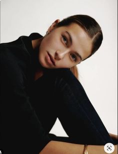 a woman is posing with her hands on her head and looking at the camera while wearing a black shirt