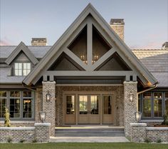 the front entrance to a large home with stone pillars and windows on either side of it