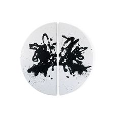 two white plates with black ink splatters on them, one is half - circle