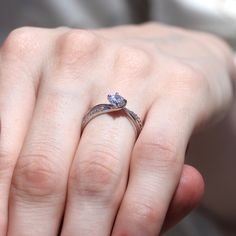 a close up of a person's hand with a diamond ring on their finger