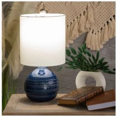 a blue and white lamp sitting on top of a wooden table next to a book