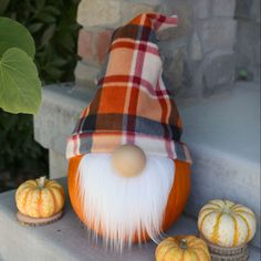 an orange and white gnome statue next to pumpkins