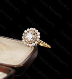 an engagement ring with pearls on it in a wooden box and some other jewelry items