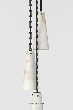 two white marble lamps hanging from a black metal pole with chains attached to the sides