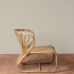 a wooden chair with a white cushion sitting on top of a brick floor next to a wall