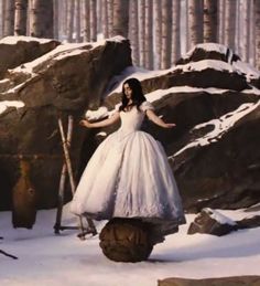 a woman in a white dress standing on top of a pile of snow covered rocks