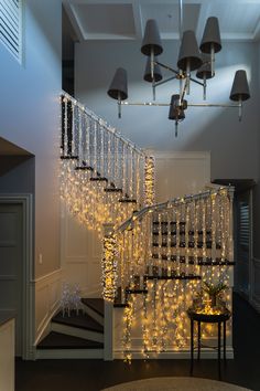 a staircase decorated with christmas lights and chandelier hanging from it's sides