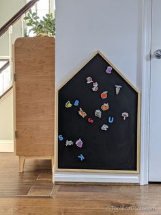 a blackboard with stickers on it next to a wooden cabinet and stair case