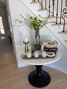 a table with candles, vases and rocks on it in front of the stairs