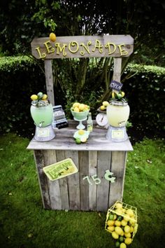 a wooden stand with yellow flowers on it in the middle of some grass and bushes