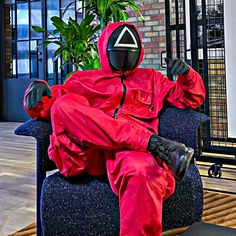 a person in a red suit sitting on a chair