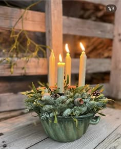 a green bowl filled with lots of candles on top of a wooden table covered in greenery