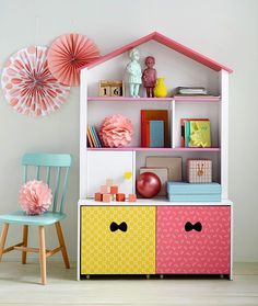 a doll house with furniture and decorations on the shelves in front of it, next to a chair