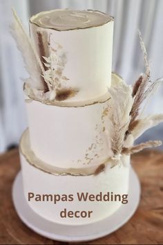 a three tiered wedding cake with feathers on top and the words pampass wedding decor above it