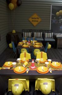 an outdoor dining area with yellow and black table cloths, plates and cups on it