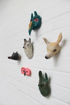 several animal heads mounted to the side of a white brick wall next to each other