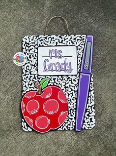 a paper bag with an apple on it and a purple pen sitting next to it