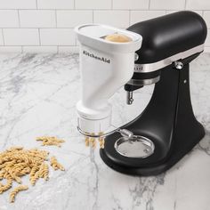 a black and white kitchen mixer on a marble counter top next to dry dog food