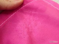 someone is stitching on the back of a pink shirt