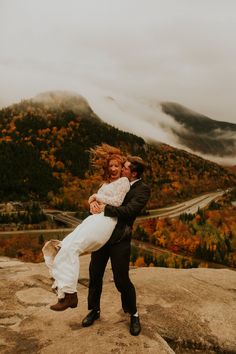 a bride and groom hug on top of a mountain during their fall wedding photoshoot