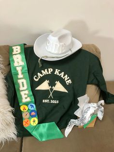 a green shirt with a white cowboy hat on top of it next to other items