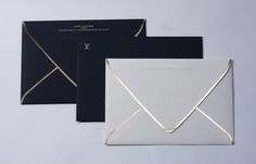 three black and white envelopes with gold foil