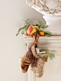 a stocking hanging from the side of a white pillar with fruit and leaves on it