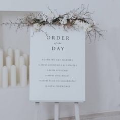 a white sign sitting on top of a wooden easel next to candles and flowers