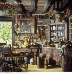 an old fashioned kitchen with lots of clutter on the table and chairs in it