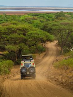 a jeep driving down a dirt road in the wild