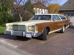 an old station wagon is parked in front of a house with brick driveway and garage