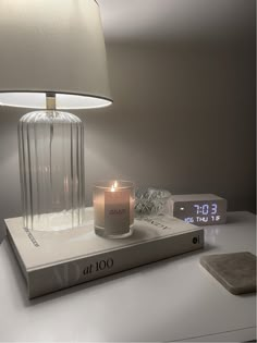 a lit candle sits on top of a book next to a clock and other items