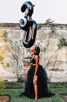 a woman in a black dress standing next to a balloon