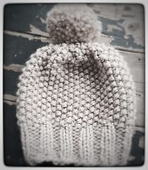 a white knitted hat sitting on top of a wooden table