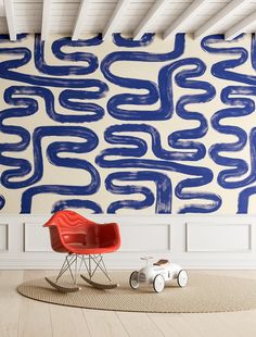 a red chair sitting on top of a rug in front of a blue and white wall