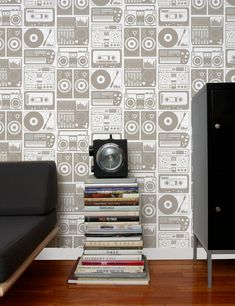 a room with a couch, bookshelf and wallpaper that has boomboxs on it