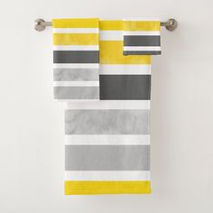 two yellow and gray striped towels hanging on a towel rack in front of a white wall