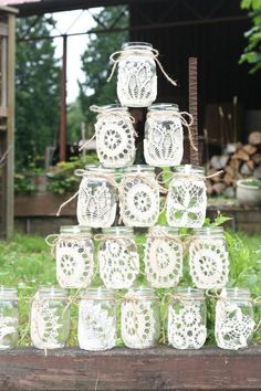 several mason jars are stacked on top of each other with lace doily around them