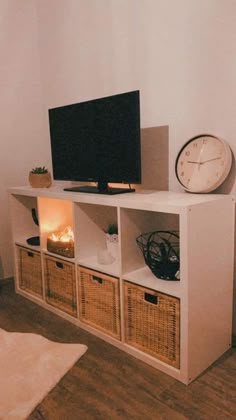 a white entertainment center with wicker baskets and a flat screen tv